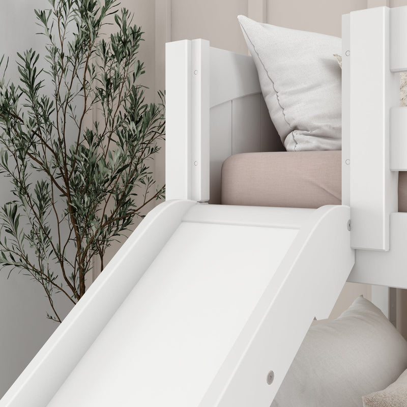 White children's loft bed with built-in slide, pale pink mattress and textured white pillow beside a potted olive tree in minimalist nursery decor
