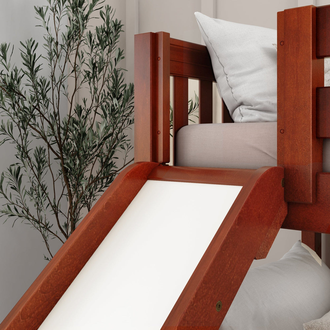 Wooden bunk bed with a slide and white cushion in a cozy room setting.