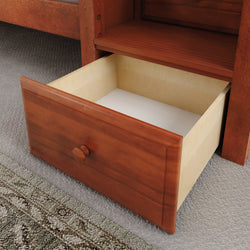 Open wooden drawer on carpeted floor, showcasing modern home storage solution.