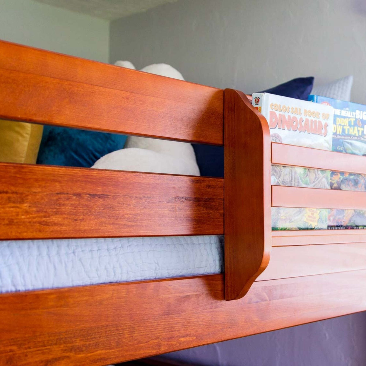 Wooden bunk bed with safety rails and colorful bedding.