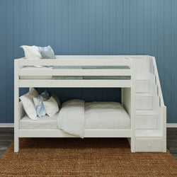 White wooden bunk bed with stairs, cozy bedding, blue wall background, and woven rug.