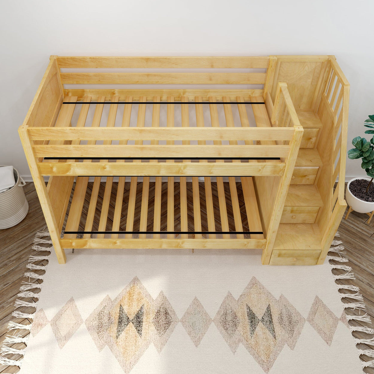 Wooden bunk bed with attached stairs on patterned rug.