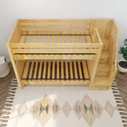 Wooden bunk bed with attached stairs on patterned rug.