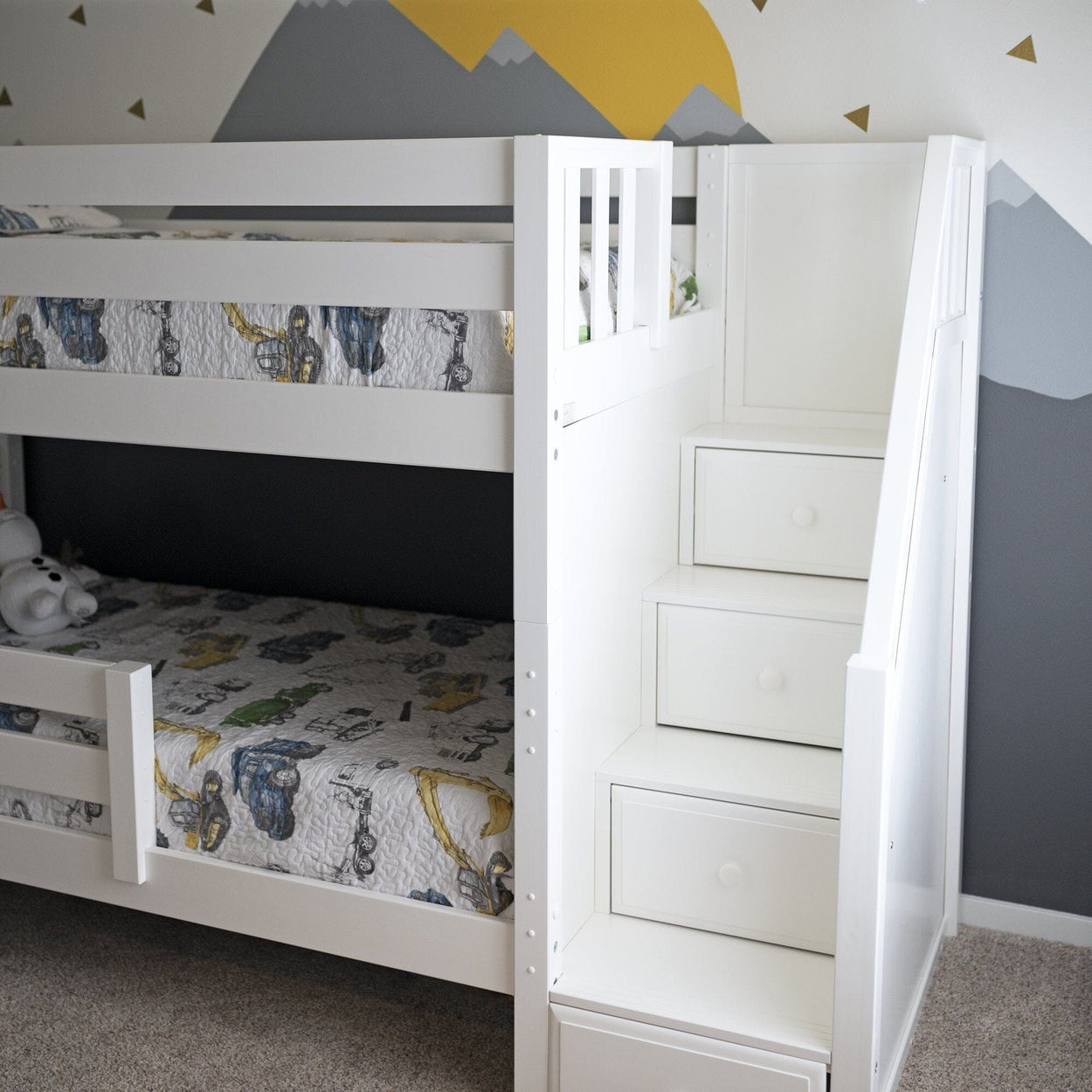 White bunk bed with built-in storage stairs in a kids' room with decorative wall art.