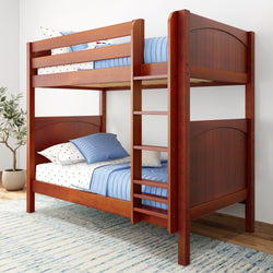 Red wooden bunk bed with blue bedding and polka dot pillows, placed in a bright room with a plant and rug.