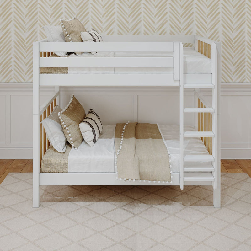 White wooden bunk bed with ladder in a kids bedroom, beige boho pillows and pom‑pom throw, chevron wallpaper, wood floor and patterned rug