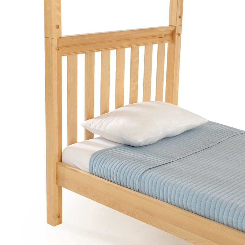 Natural wood slatted headboard and twin bed frame with white pillow and light blue quilted blanket