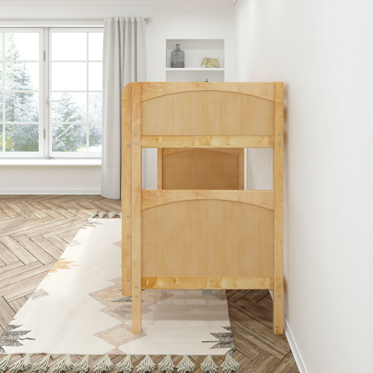 Side view of a wooden crib in a cozy nursery with large window and neutral decor.