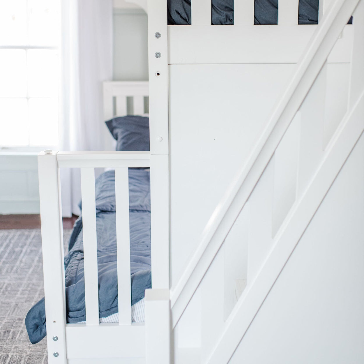 White wooden bunk bed with blue bedding in a bright room.