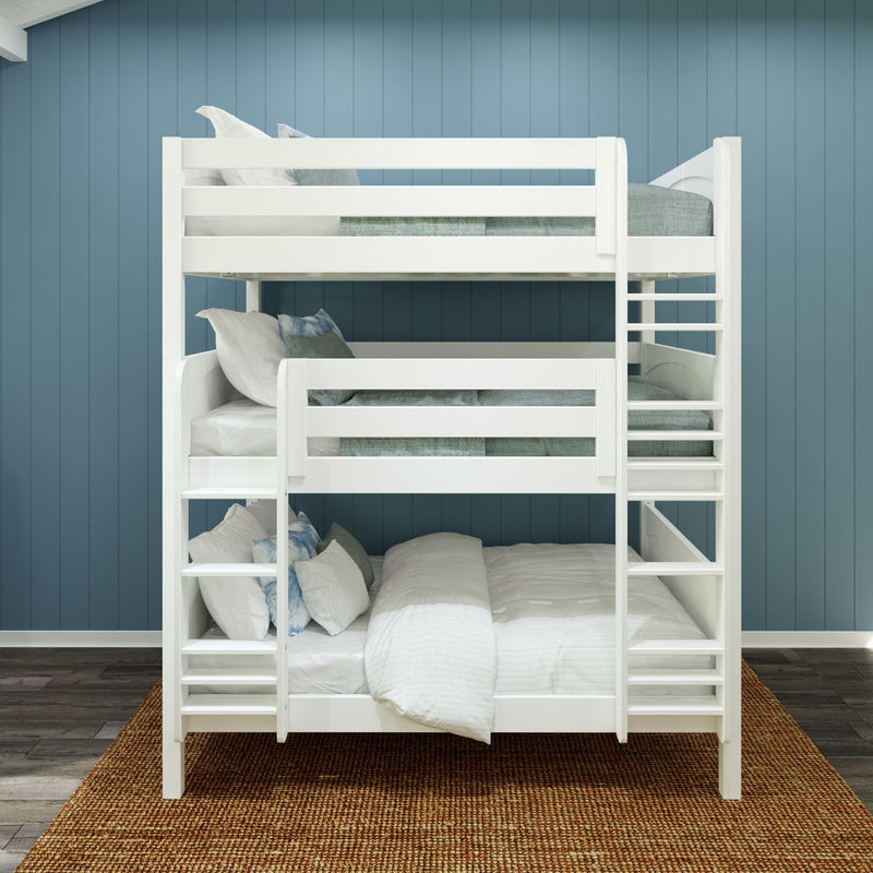 White wooden triple bunk bed with ladder, light teal bedding and decorative pillows in a kids' bedroom against a blue shiplap wall on a woven jute rug