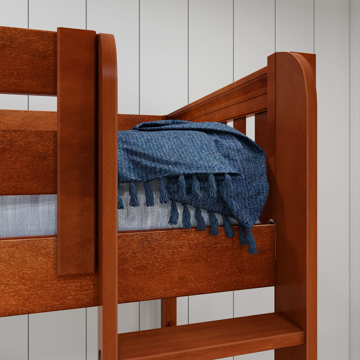 Wooden bunk bed with blue textured blanket in cozy bedroom setting.