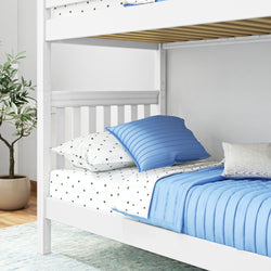White wooden bunk bed with blue bedding and star-patterned sheets in a cozy bedroom.