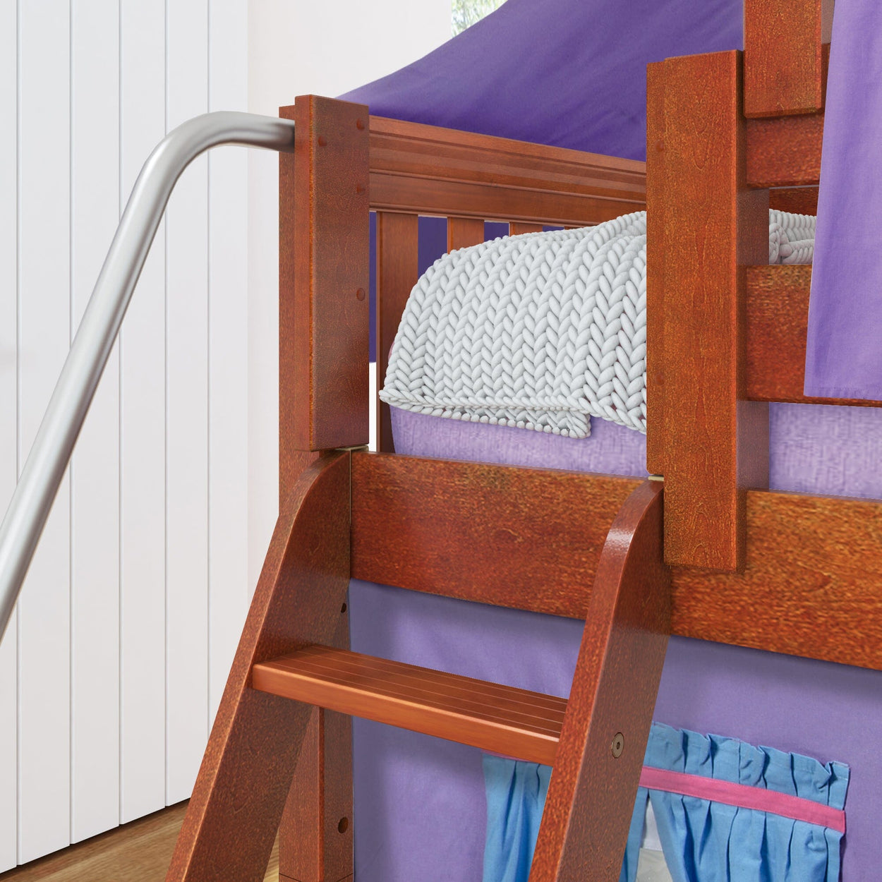 Wooden loft bed with purple canopy and slide, featuring a cozy knitted blanket.