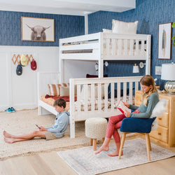 Children's bedroom with bunk beds and blue accent wall, featuring two kids engaged in reading and device use, enhancing family lifestyle.
