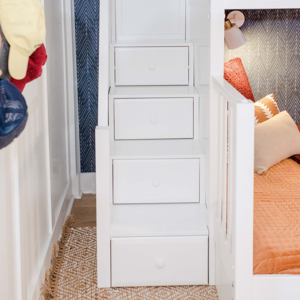 White bunk bed stair drawers with cozy bedding and decorative pillows in a modern bedroom setting.