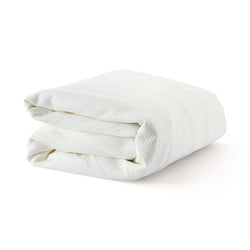 Folded white waffle blanket on a plain background.