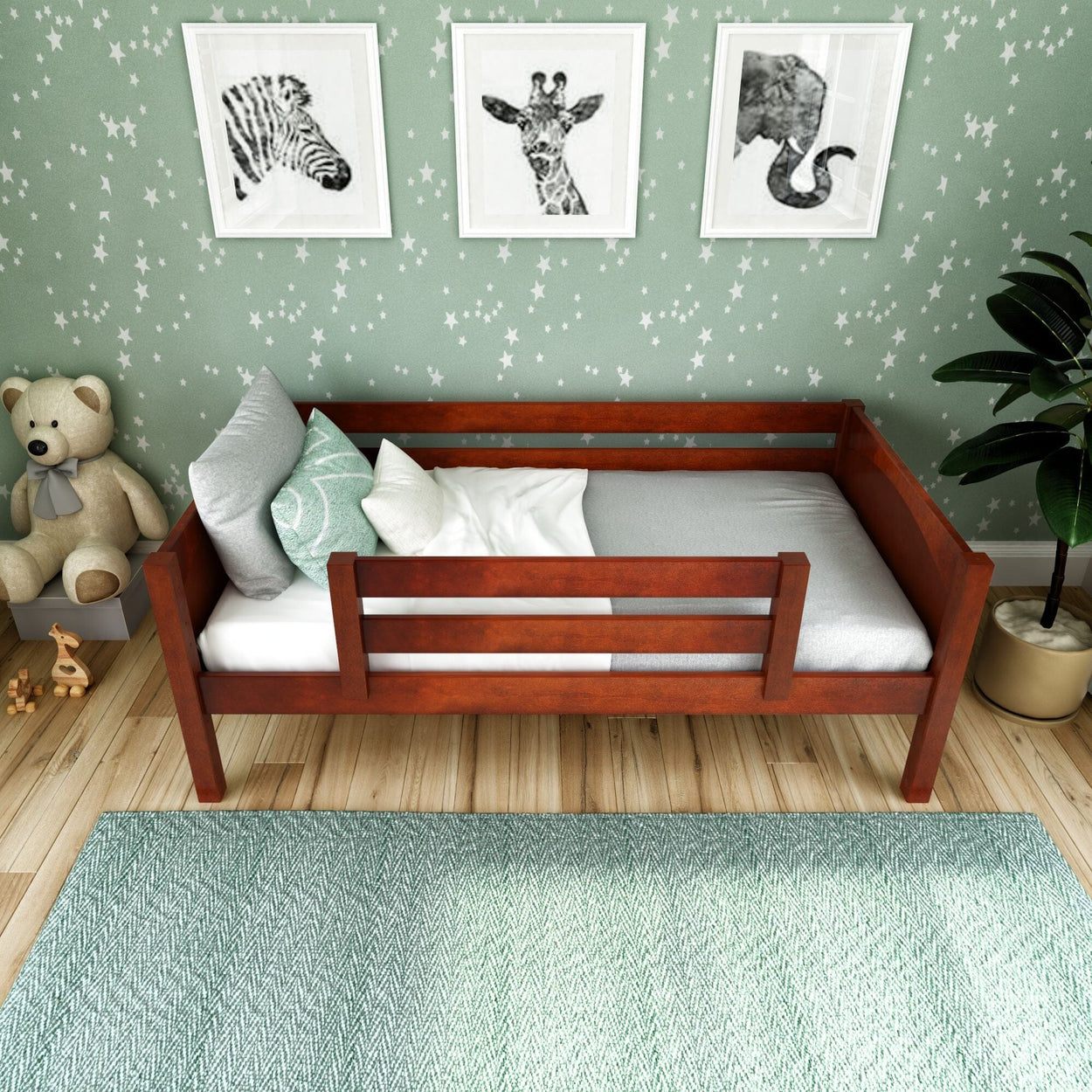 Wooden toddler bed with railing in a star-themed nursery room with green decor and animal prints.