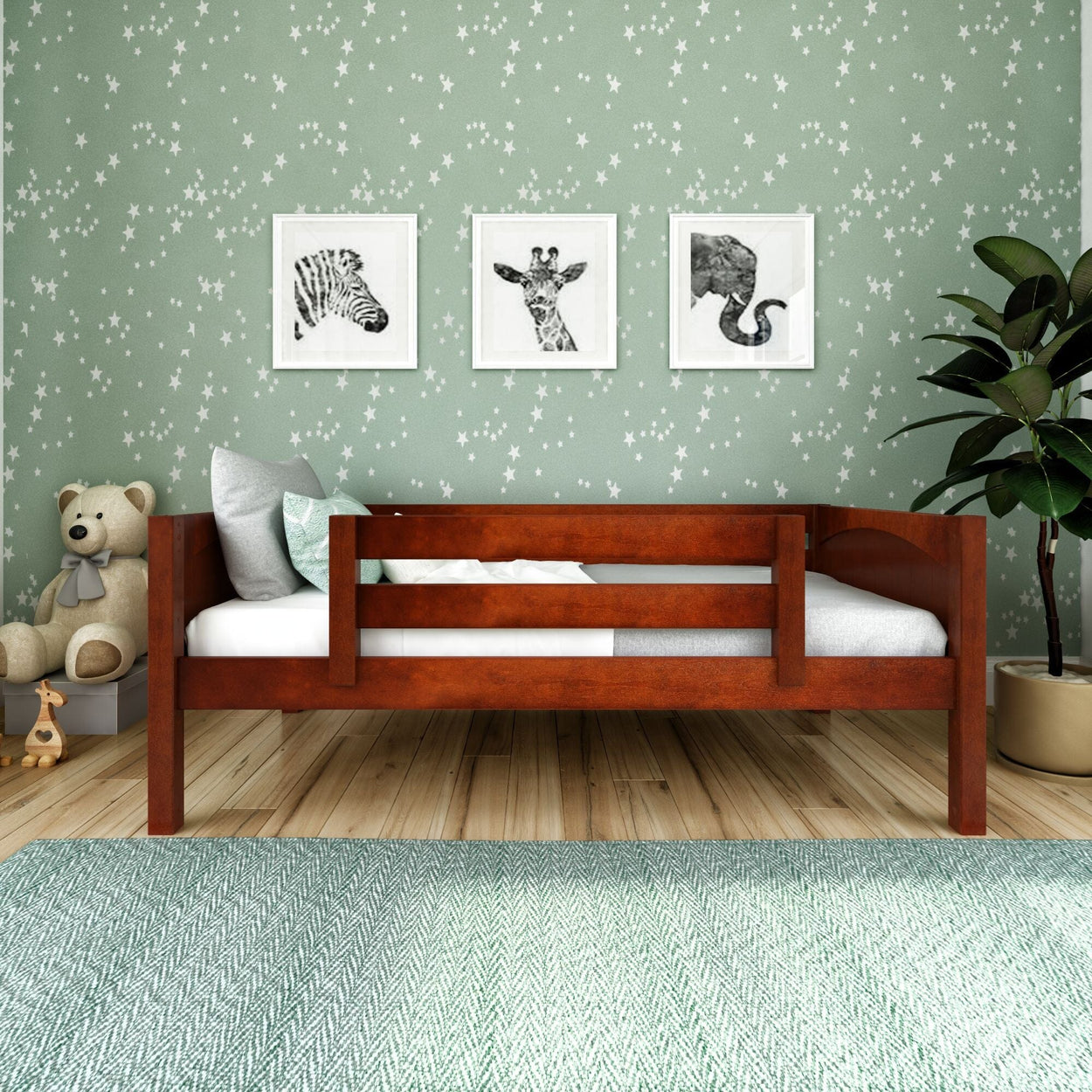 Wooden toddler bed with giraffe, zebra, elephant wall art and green star wallpaper.