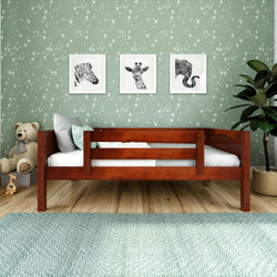 Wooden toddler bed with giraffe, zebra, elephant wall art and green star wallpaper.