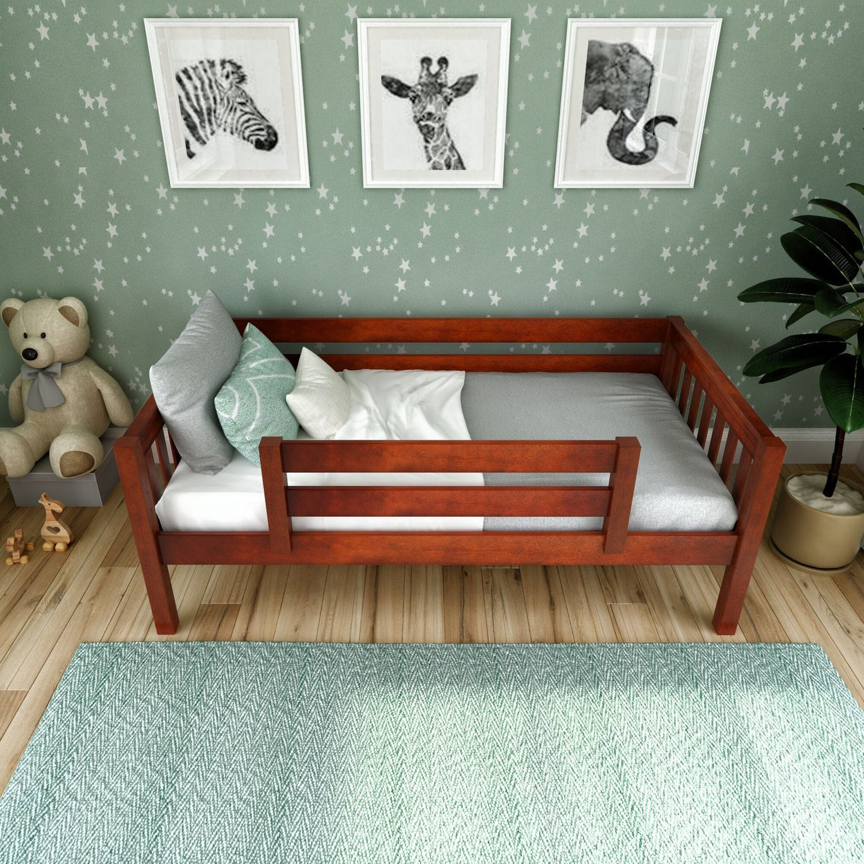 Wooden toddler bed with grey bedding in a star-themed nursery, featuring animal artwork and plush teddy bear decor.