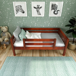 Wooden toddler bed with grey bedding in a star-themed nursery, featuring animal artwork and plush teddy bear decor.