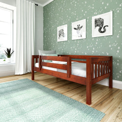 Wooden toddler bed in a nursery with green star-patterned wallpaper and animal prints.