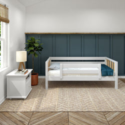 Modern toddler bed with white wood design in a stylish bedroom featuring a blue accent wall, indoor plant, and natural light.