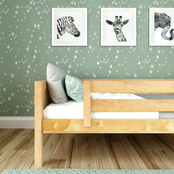 Wooden bed frame in children's room with star-patterned wallpaper and animal art prints.