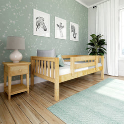 Children's bedroom with wooden toddler bed, green starry wallpaper, and framed animal art above the bed.