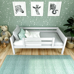 Toddler bed with safety rails in a green-themed nursery featuring animal wall art and wooden floor.