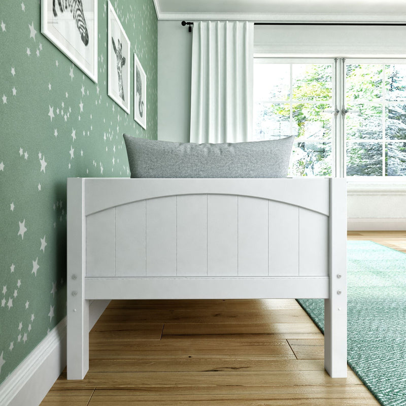 White toddler bed headboard against mint green star wallpaper in a bright nursery with framed animal prints, gray pillow, white curtains, hardwood floor and teal rug