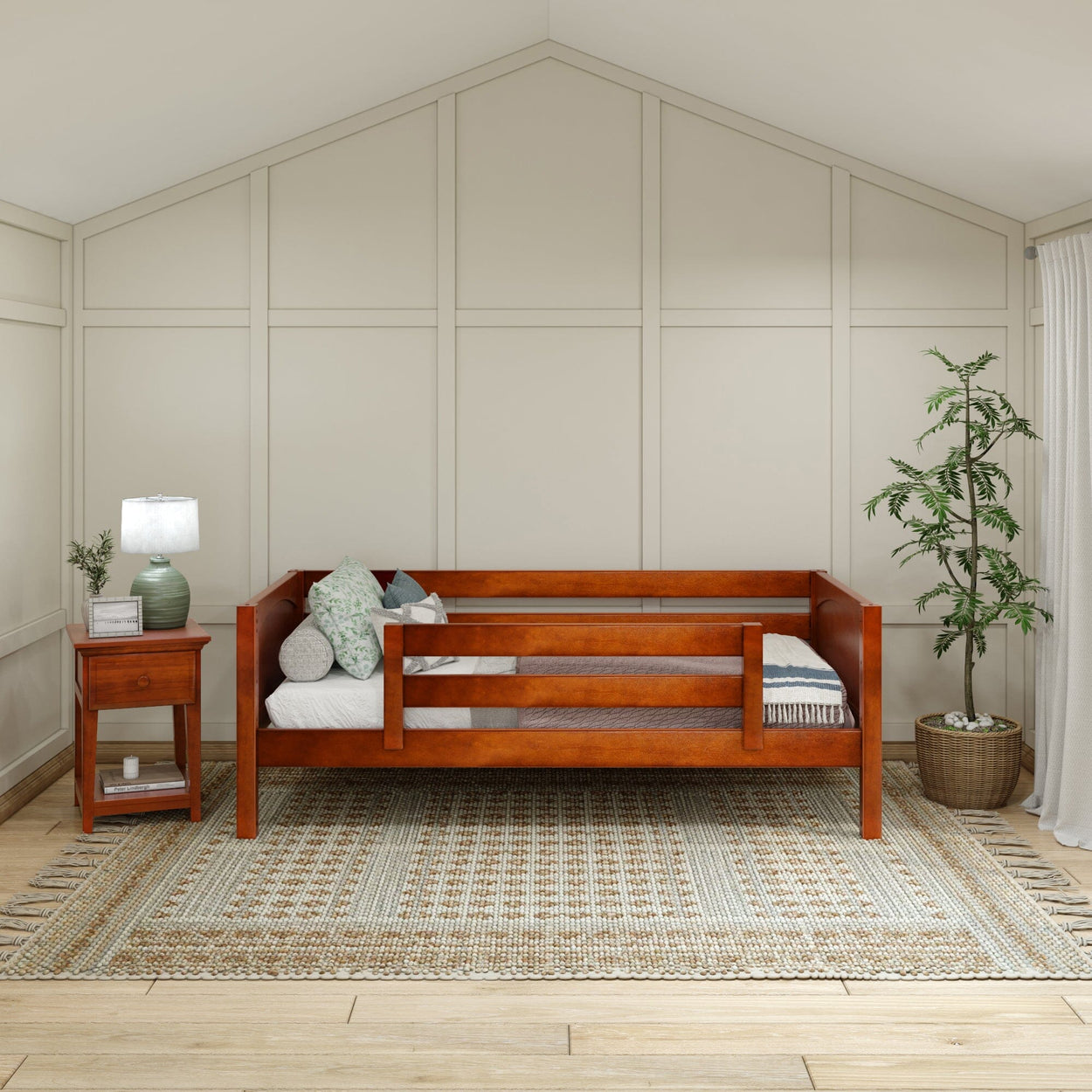 Wooden daybed with side rails in a cozy, modern bedroom featuring a potted plant and a bedside table with a lamp on a patterned rug.