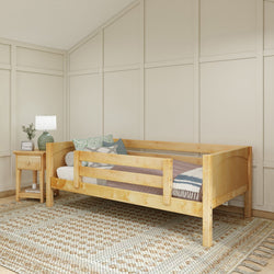 Wooden toddler bed with guardrails in a cozy bedroom setting featuring a nightstand and decorative lamp.