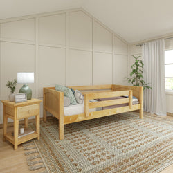 Cozy bedroom with wooden daybed, decorative pillows, nightstand with lamp, and woven area rug near large window.