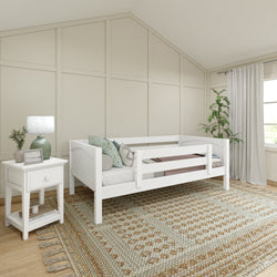 Cozy children's bedroom with white wooden bed, decorative pillows, bedside table, lamp, and patterned rug.