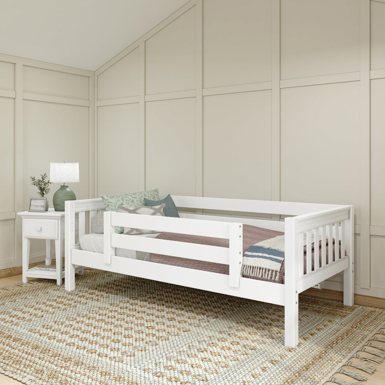 White wooden daybed with guardrails, cozy pillows, and a side table in a modern bedroom setting.