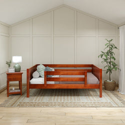 Warm and cozy wooden daybed with green cushions in a serene bedroom setting, featuring a potted plant and a wooden nightstand with a lamp.