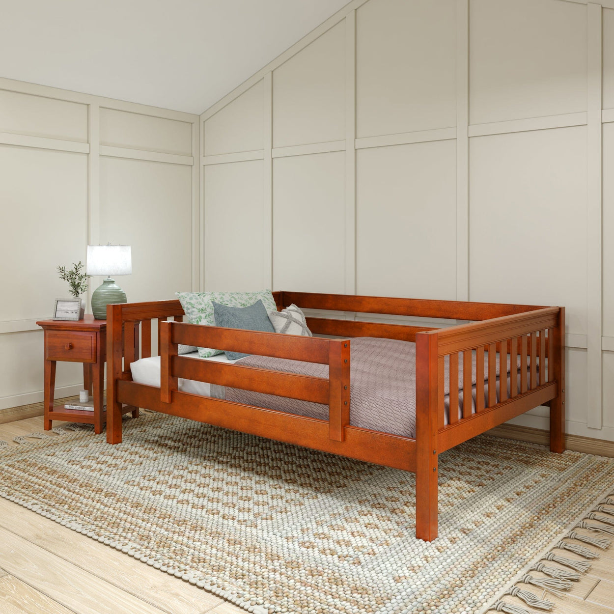 Wooden daybed with beige bedding and decorative pillows in a modern bedroom setting with a nightstand and lamp.
