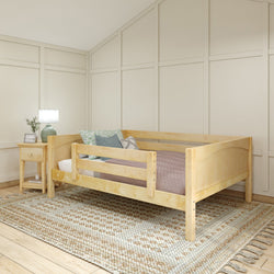 Wooden toddler bed in cozy bedroom with beige walls, a textured area rug, and a bedside table with a lamp.