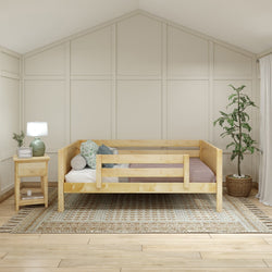 Cozy minimalist bedroom with a light wood bed, nightstand, green plant, and woven rug.