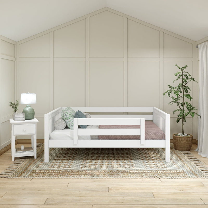 Neutral nursery with white toddler bed, board-and-batten accent wall, green bedside lamp, textured woven rug and potted plant