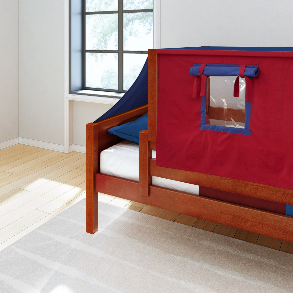 Red and blue kids bed tent on a wooden frame in a bright room with a large window.