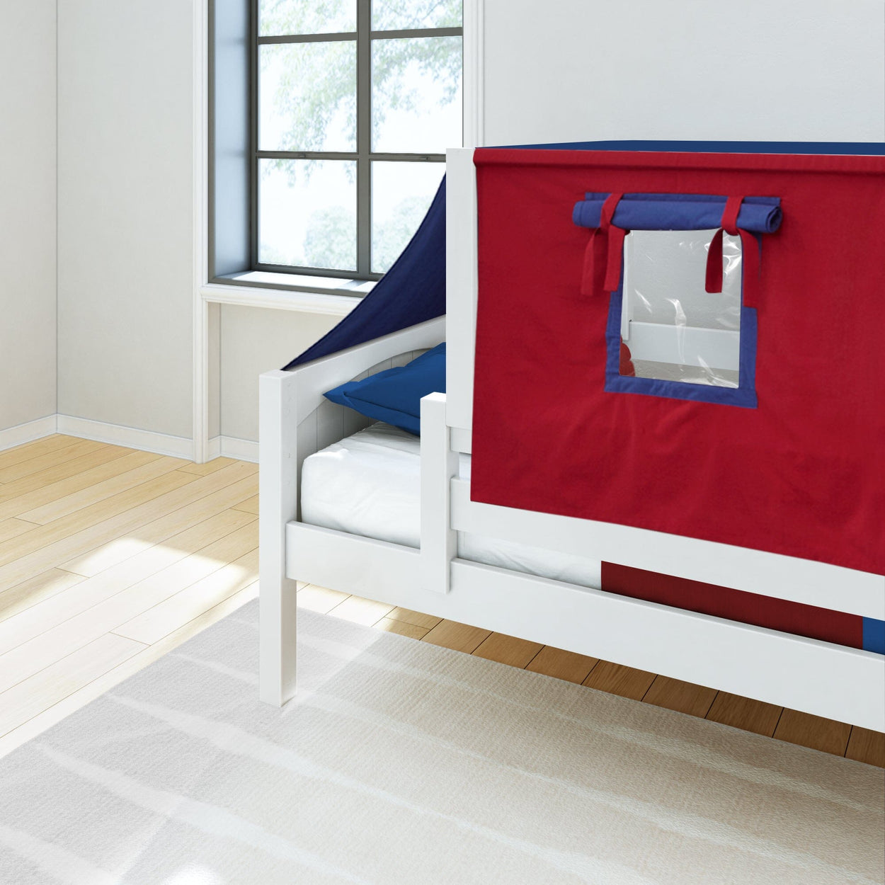 Red and blue tent-style bed cover on a white children's bed in a bright room with natural light.