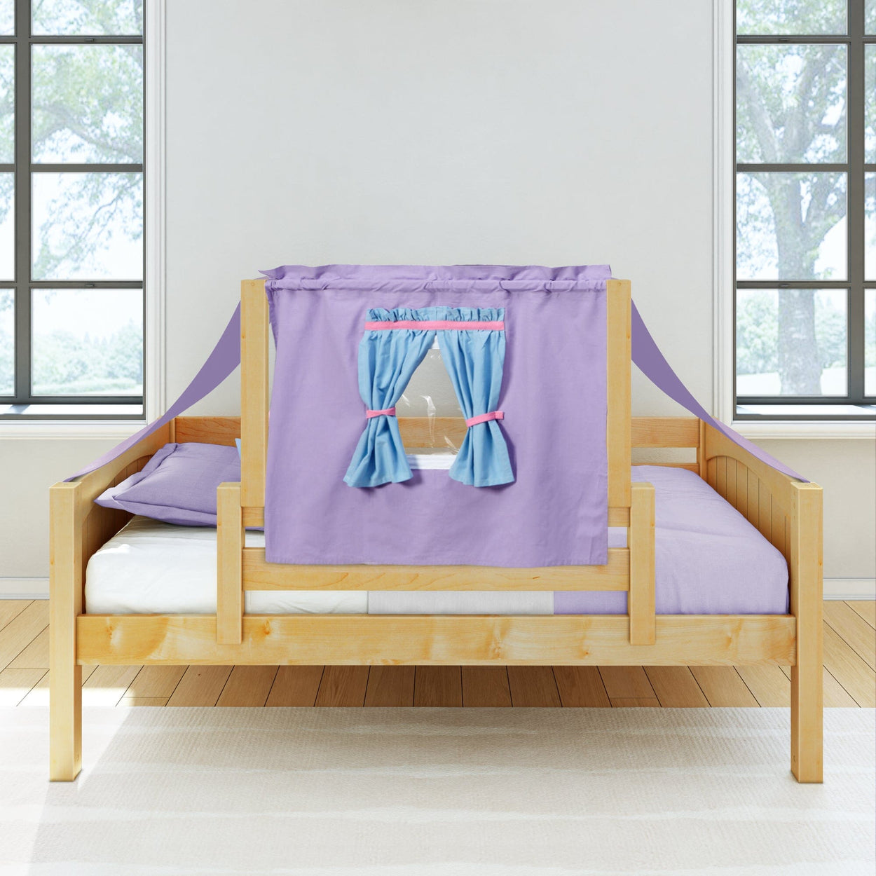 Wooden children's bed with purple and blue curtain tent canopy in a bright room with large windows.