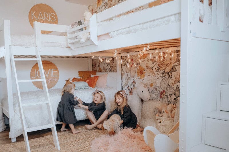 White twin over twin bunk corner bunk and loft bed in bright girls room with colorful wallpaper
