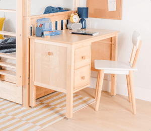 Natural Desk with Natural and white chair in a room with a Low loft bed to the left and plant to the right.