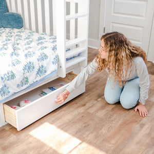 Girl opening up an underbed drawer on her white bunk bed.
