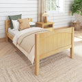 Cozy farmhouse bedroom with wooden bed, neutral bedding, woven pillows, bedside lamp, shiplap wall and wicker plant basket.