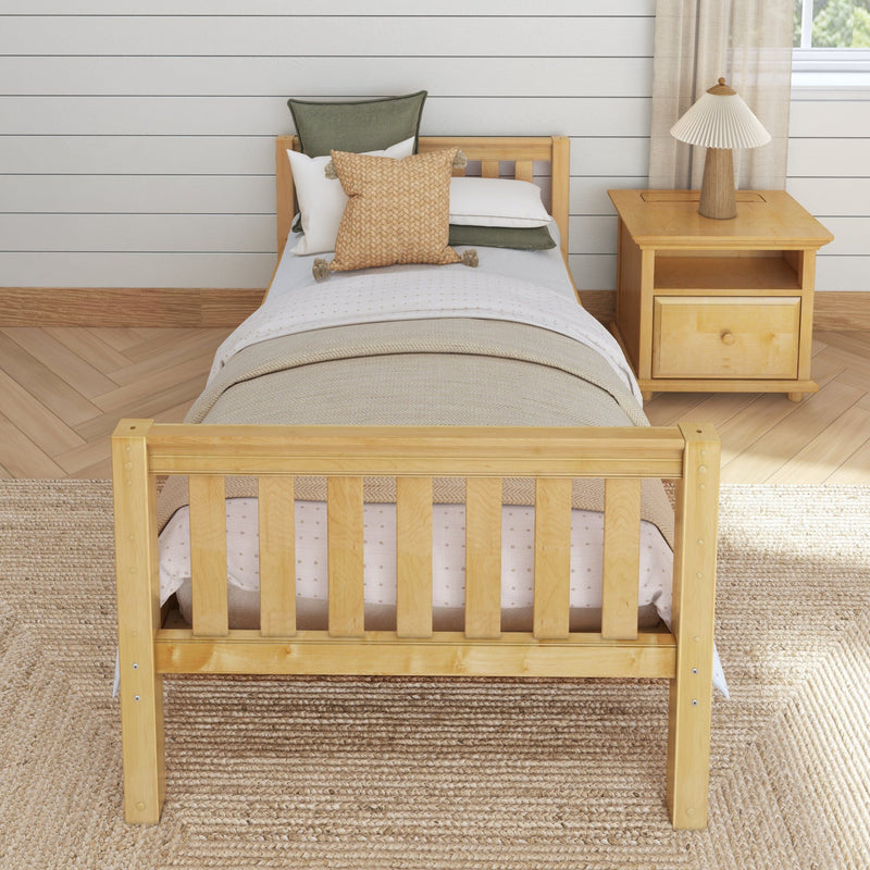 Cozy neutral farmhouse bedroom with twin wooden bed, woven throw pillow and green linen cushions, wooden nightstand and pleated lamp against white shiplap wall