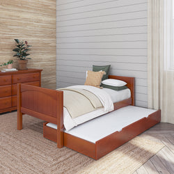 Wooden twin bed with trundle in bright bedroom featuring cozy bedding, dresser, and potted plant.